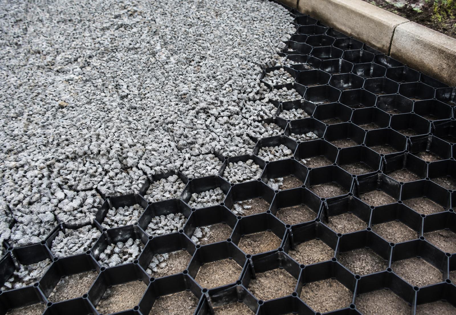 GEOHEX cellular grid half filled with grey aggregate beside a concrete edge